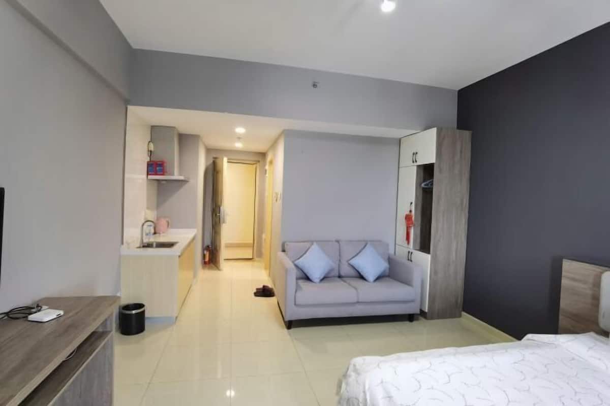 Une chambre d’hôtel moderne équipée d’un lit, d’un canapé, d’une kitchenette et d’une armoire.