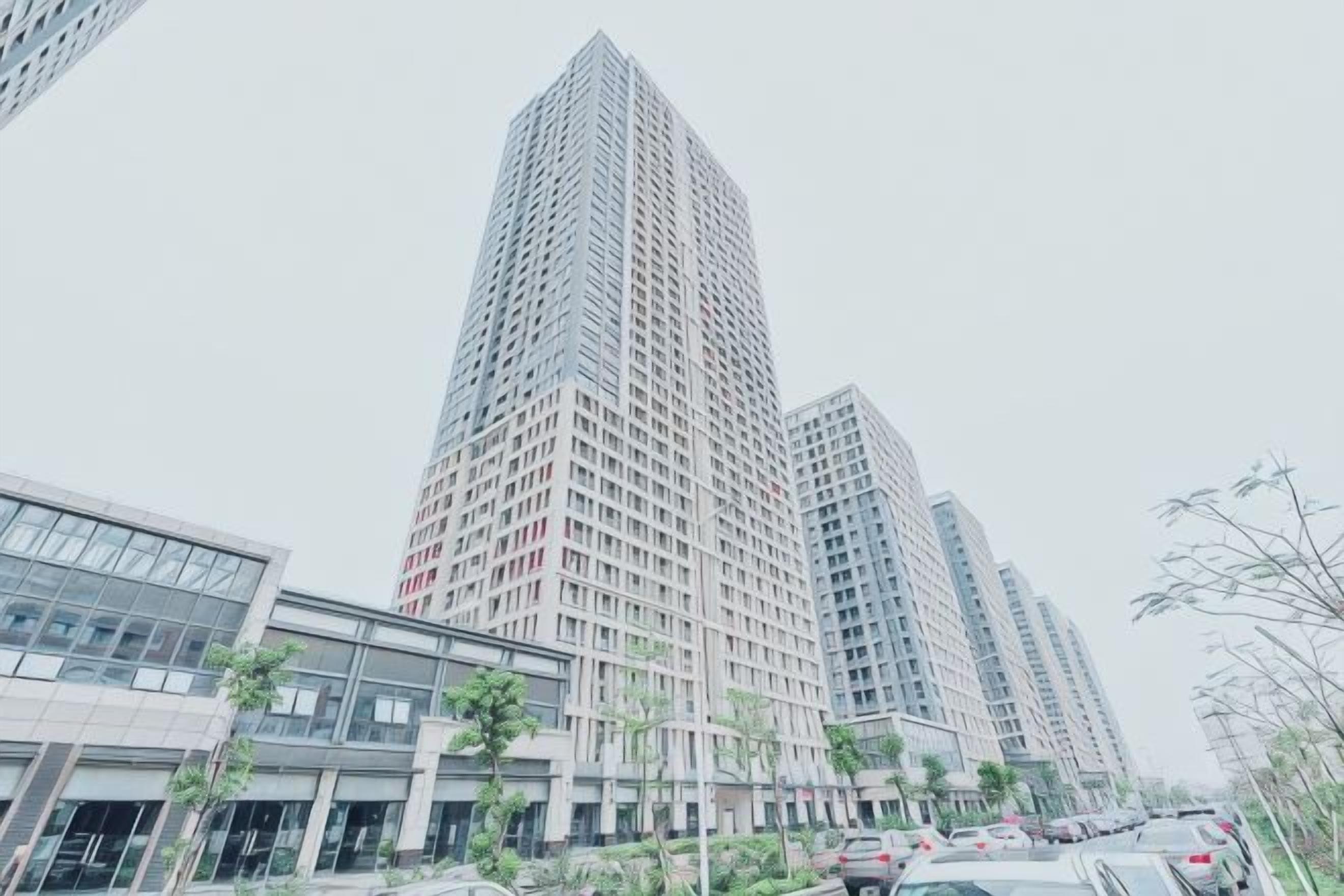 A high-rise building with a modern architectural design, surrounded by other buildings and trees.