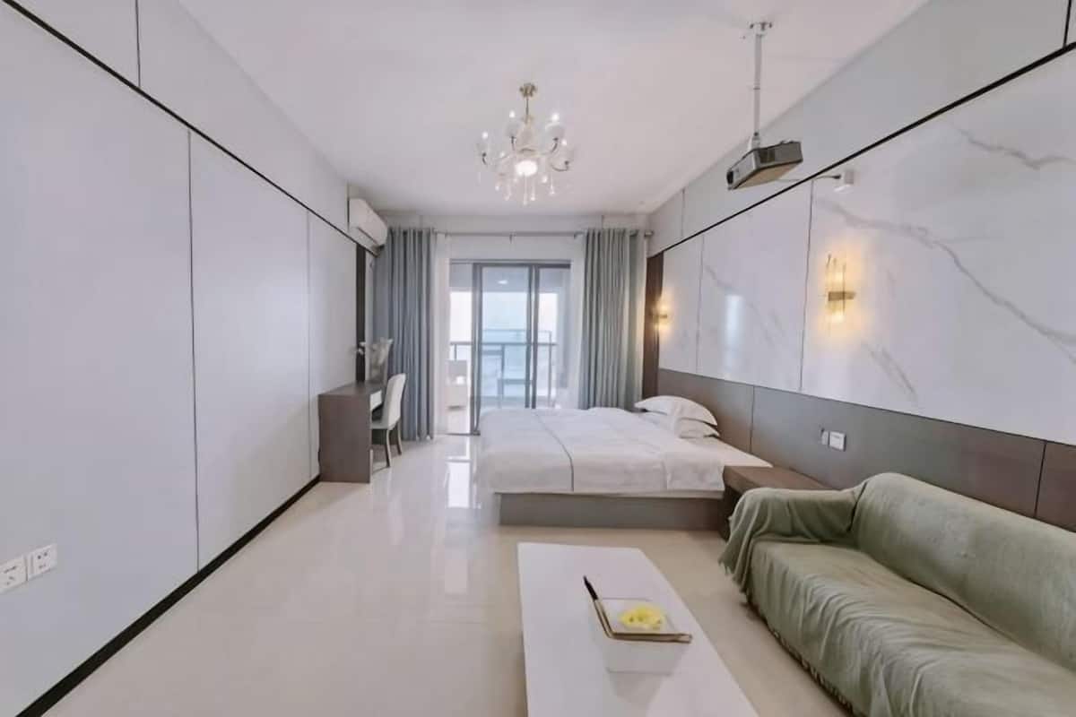 Une chambre moderne avec un lit, un canapé, un bureau et une vue sur l’extérieur.