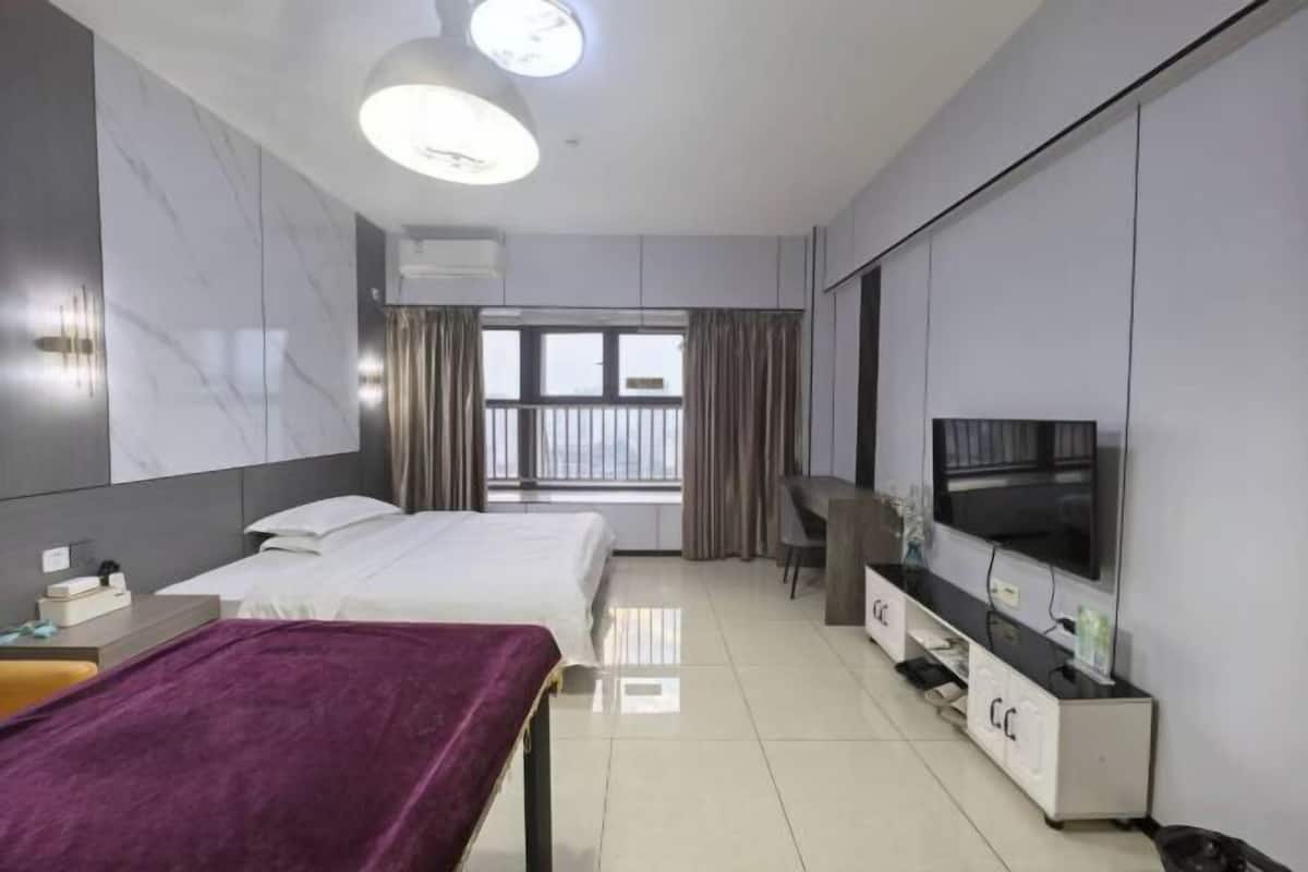 Une chambre d’hôtel avec deux lits, un bureau, une télévision et une fenêtre avec des rideaux.