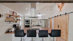Une cuisine moderne dotée d’un îlot central, de tabourets de bar et de meubles de rangement en bois.