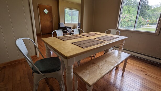 Un coin repas comprenant une table en bois, quatre chaises et un banc.
