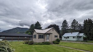 Une maison de plain-pied avec un toit en pente, un porche à l’avant et un petit jardin devant la maison.