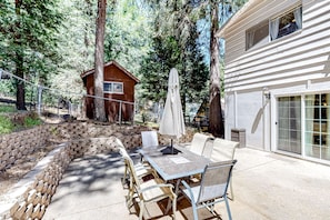 Relax in a serene outdoor space with a dining table and six comfortable chairs, shaded by an umbrella.
