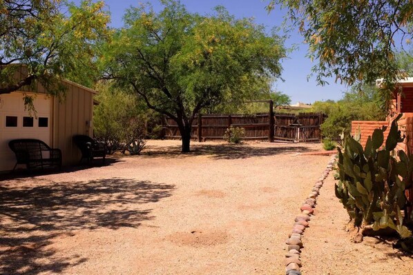 Un patio con un edificio, una cerca de madera y una planta de cactus.