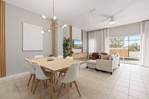 Una sala moderna con comedor, un sofá y un televisor.