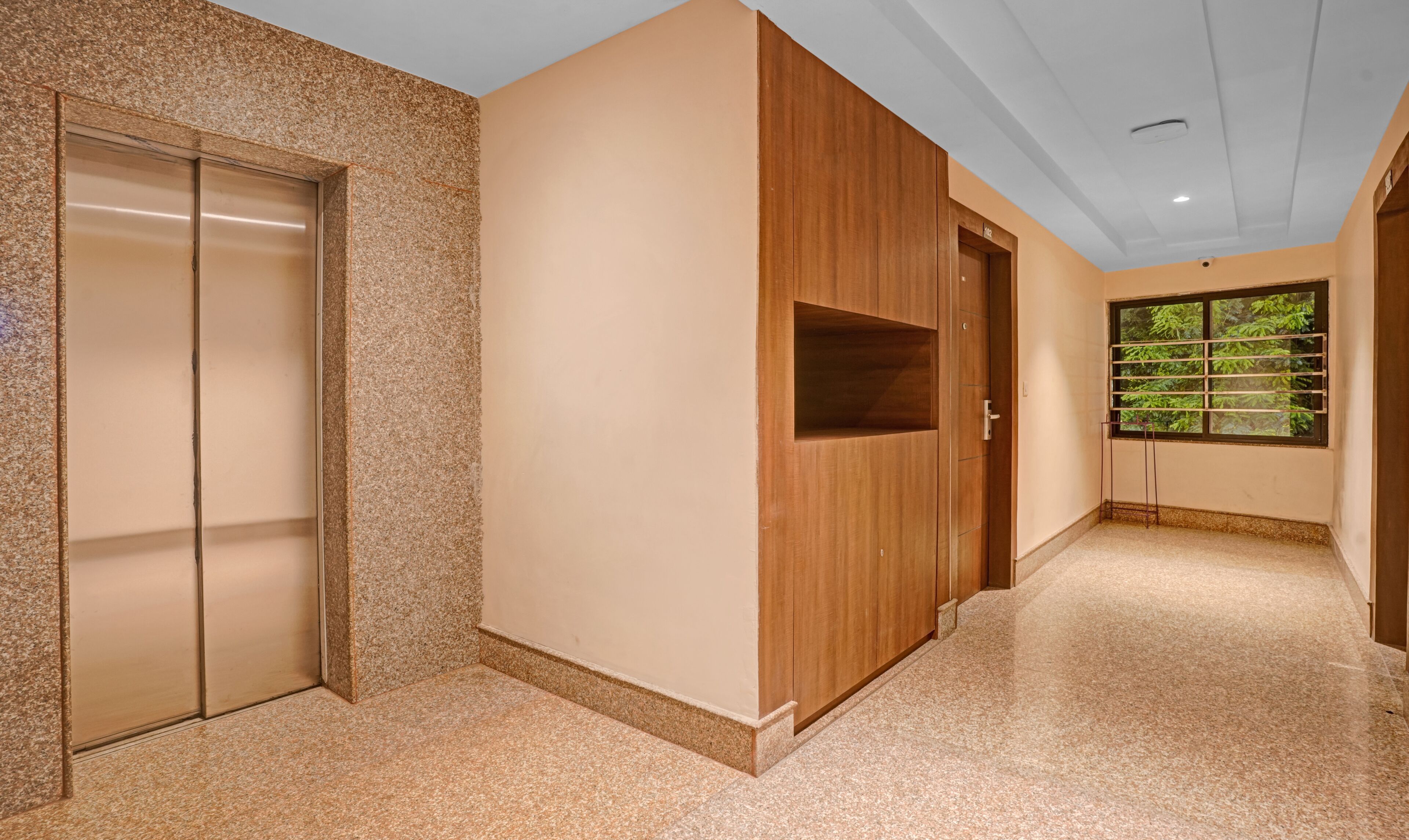 Ein Flur mit Granitboden, einem Holzschrank und einer Tür mit Fenster.