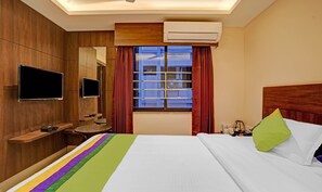 Une chambre d’hôtel équipée d’un lit, d’une télévision, d’un bureau, d’une fenêtre avec des rideaux et d’un climatiseur.