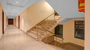 Ein Hotelgang mit Teppichboden, einer Treppe mit Metallgeländern und einem an der Wand befestigten Feuerlöscher.