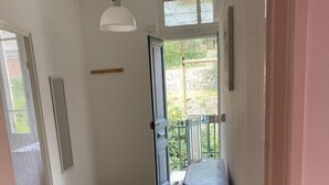 A hallway with patterned floor tiles, a wooden cabinet, a white pendant light, and a door leading to a balcony. - Apartment (Imperia)