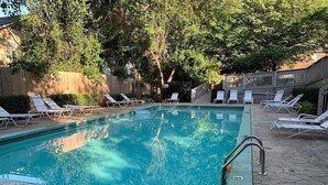 A swimming pool with lounge chairs and a wooden fence in the background. - Cozy Condo * Office* Near Luxury Mall & Uptown (Charlotte)
