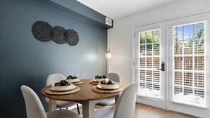 A dining area with a round table, four chairs, and a wall-mounted light fixture. - Cozy Condo * Office* Near Luxury Mall & Uptown (Charlotte)