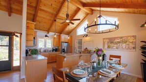 A spacious kitchen with wooden cabinets, a central island, and a dining area with a large table set for four. - Mountain Retreat, Pool+Great Views, 30 days (Carmel Valley)