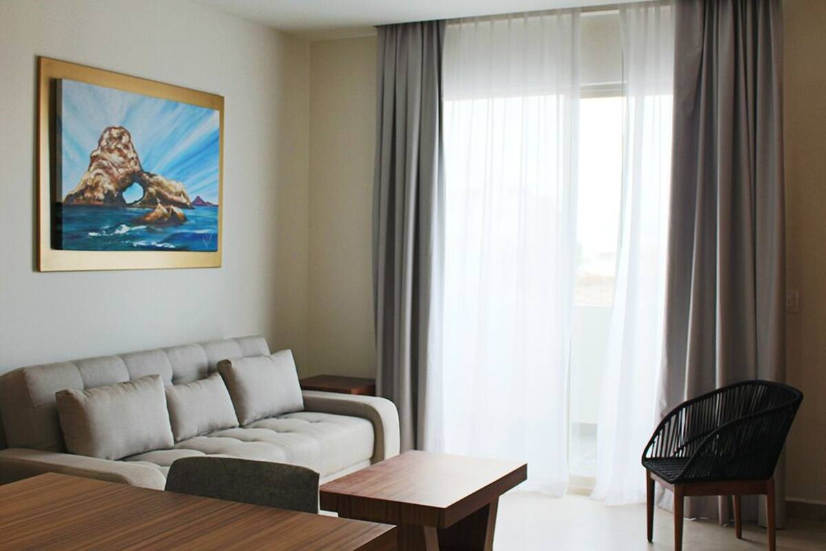 Un salon moderne avec un canapé, une table à manger et une chaise. Il y a un tableau au mur et une fenêtre avec des rideaux.