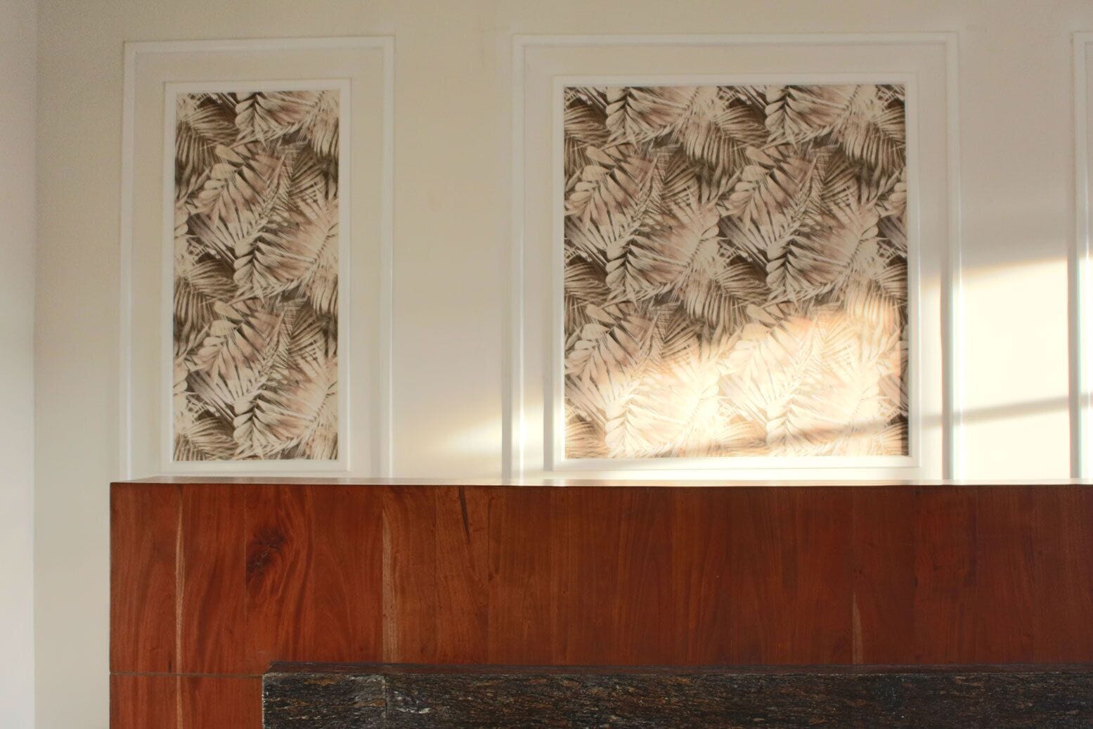 Pared con dos láminas botánicas enmarcadas y un panel de madera debajo.