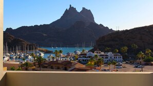 Een kustjachthaven met boten, een opvallende berg op de achtergrond en een mix van woon- en bedrijfsgebouwen.