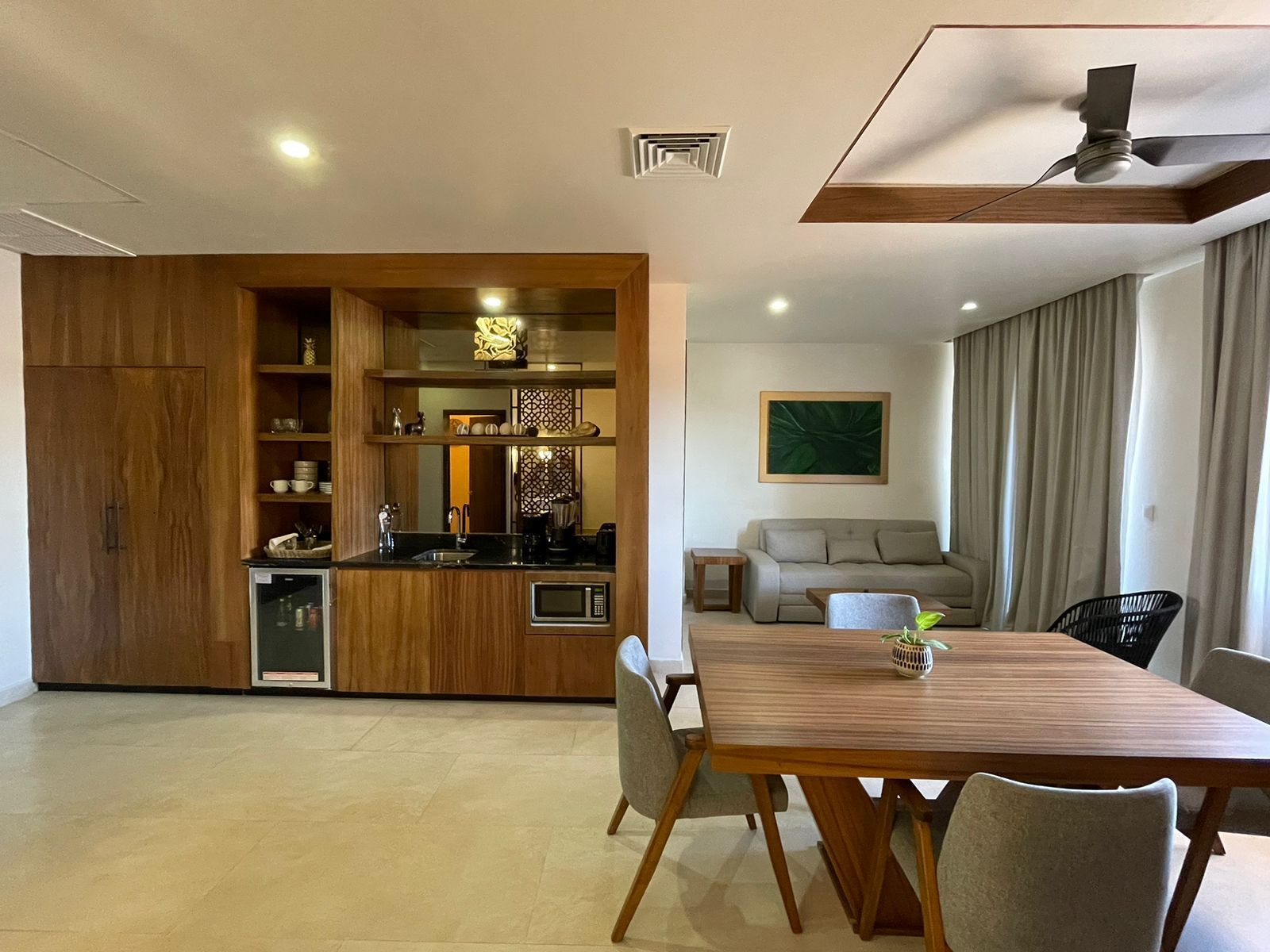 Una cocina moderna con armarios de madera, microondas integrado y comedor con mesa y sillas de madera.