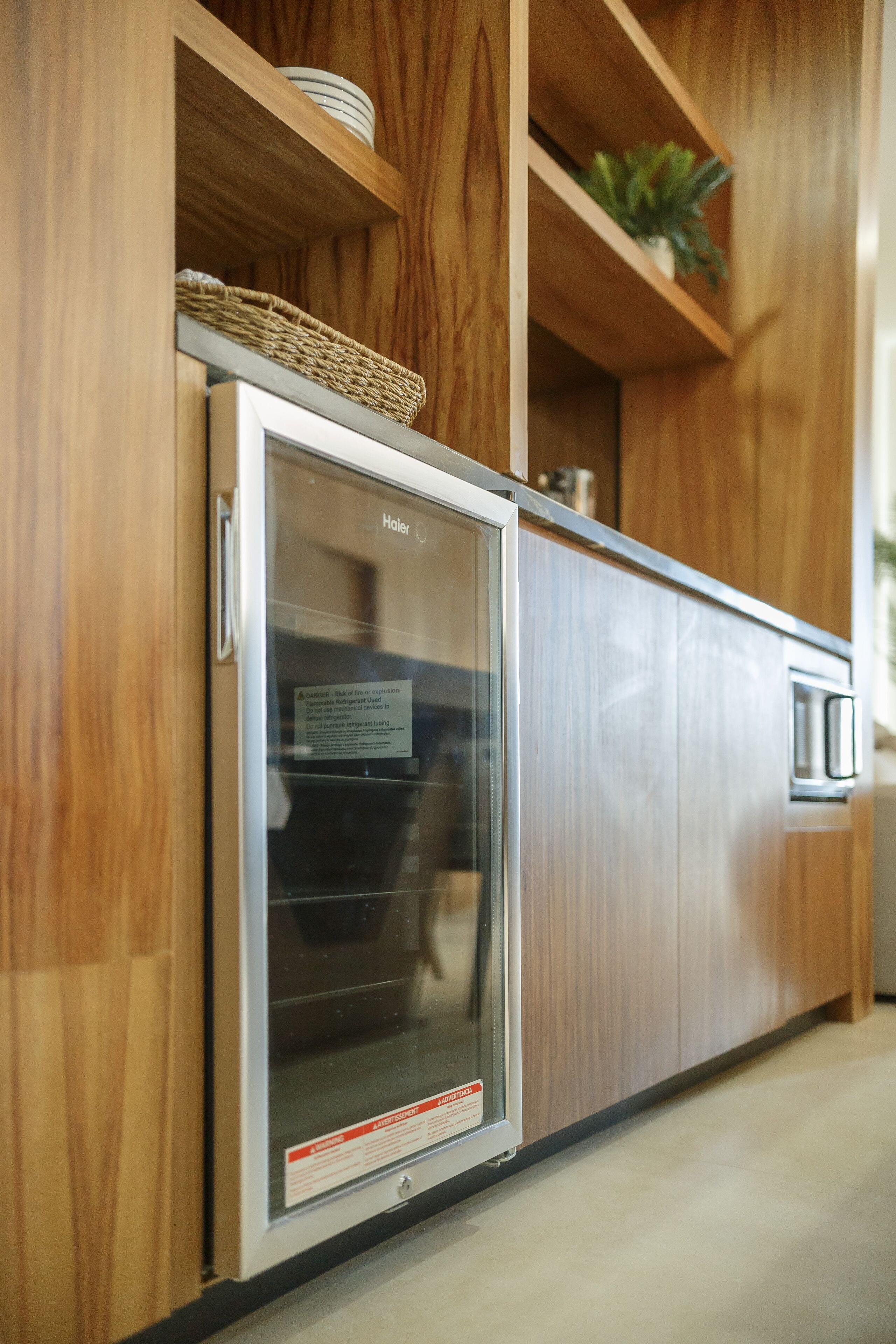 A modern kitchen with wooden cabinetry, a stainless steel refrigerator, and a microwave.