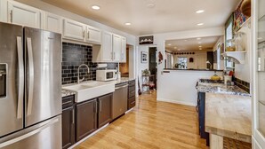 A modern kitchen with stainless steel appliances, a black tiled backsplash, and wooden flooring. - Quiet 2 BR near RiNo w/ sunroom & large backyard (Denver)