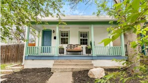 A house with a porch, steps leading to the door, and a small garden area. - Quiet 2 BR near RiNo w/ sunroom & large backyard (Denver)
