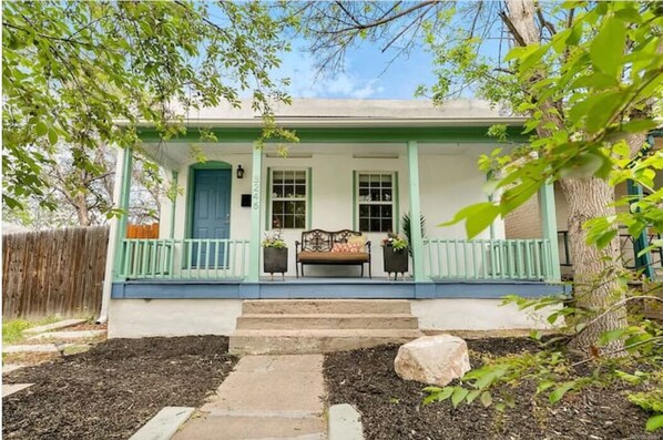 A house with a porch, steps leading to the door, and a small garden area.