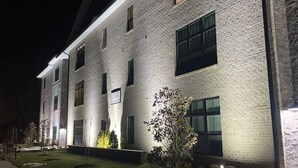 En moderne bygning med facade i mursten, store vinduer og en godt oplyst indgang.
