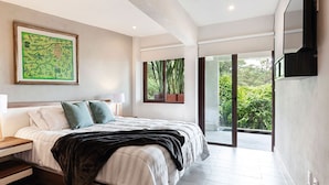 A modern bedroom with a bed, a nightstand, a large window, and a view of greenery outside. - Moderna Villa con Hermosa Vista al Lago (Valle de Bravo)