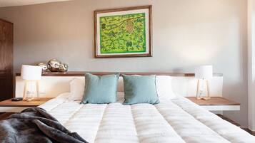 A neatly made bed with two pillows, a bedside table with a lamp, and a framed picture on the wall.