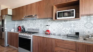 A modern kitchen with wooden cabinets, a stainless steel stove, a microwave, and a patterned backsplash. - Moderna Villa con Hermosa Vista al Lago (Valle de Bravo)