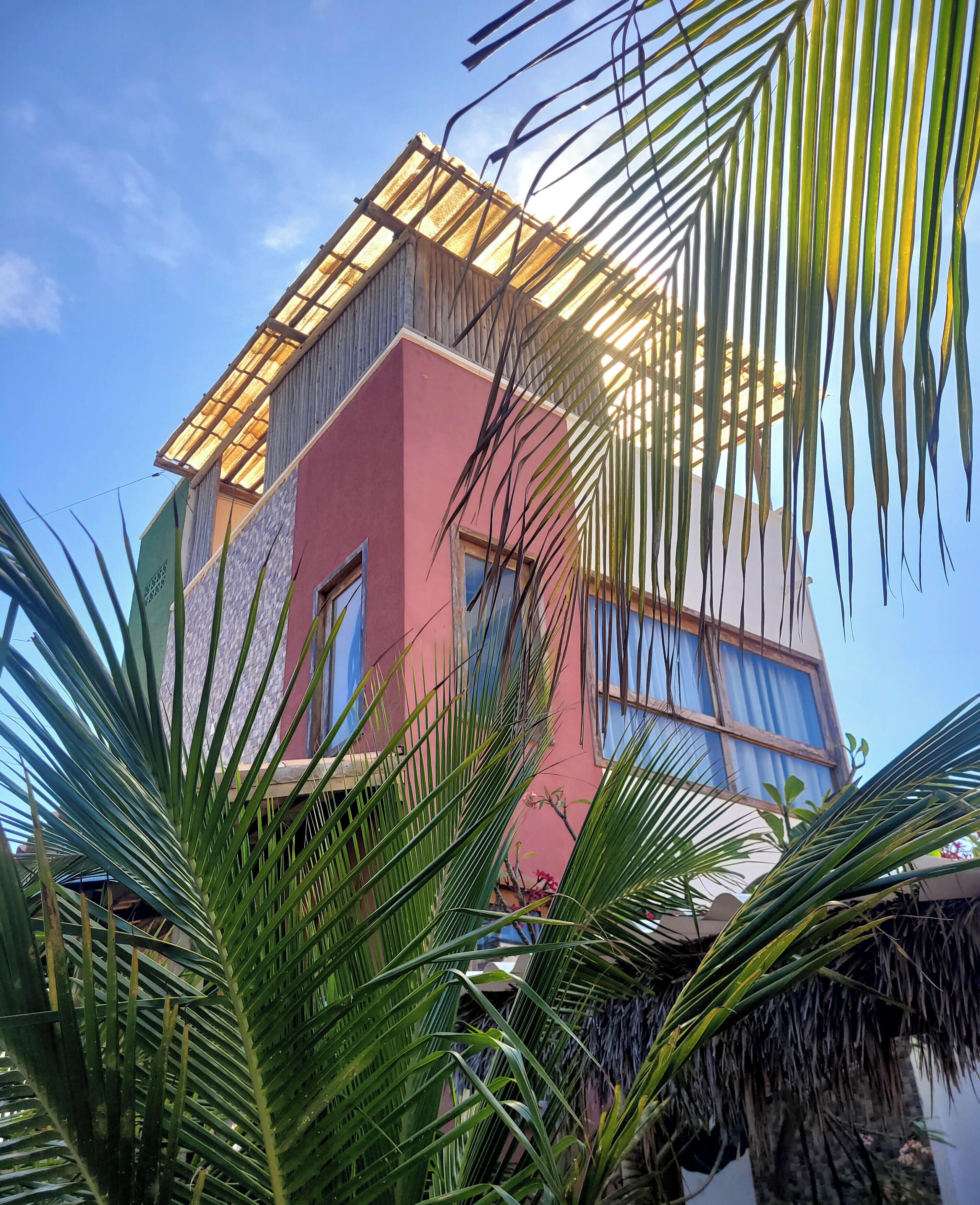 A modern building with a pink facade, large windows, and a flat roof.