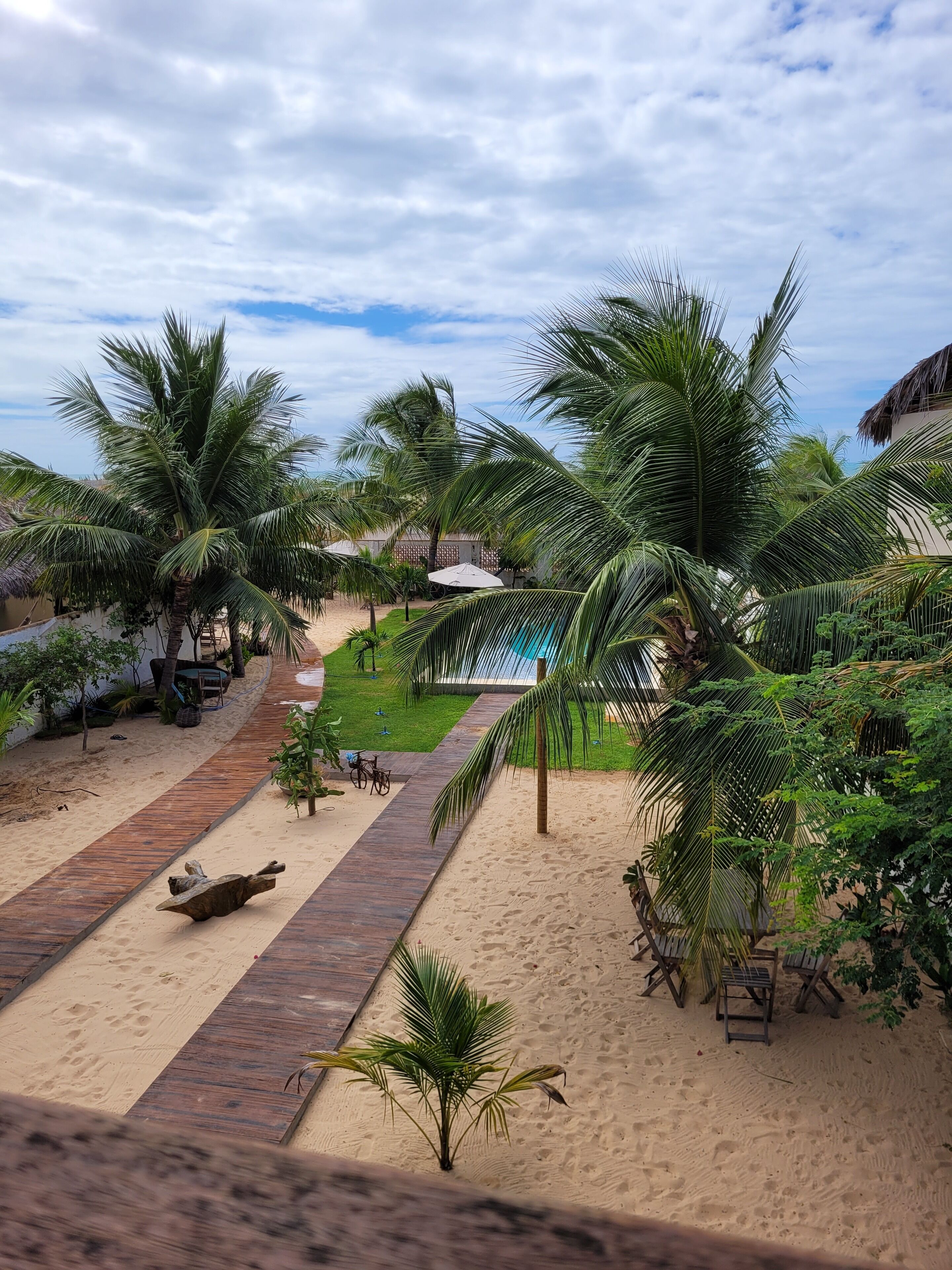 A resort with a pool, palm trees, and a sandy walkway.