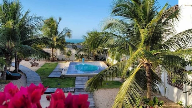 Zona de piscina con palmeras, una piscina pequeña y un sendero.