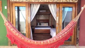Una habitación con cama, cortinas y una hamaca.