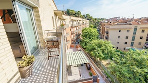 Un balcón con vistas a un paisaje urbano, una planta en maceta y mobiliario exterior.
