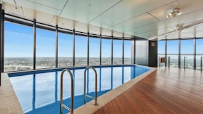 Una piscina interior moderna con amplias ventanas que ofrecen vistas de la ciudad.