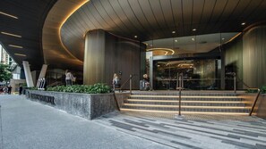 A modern building entrance with a curved ceiling, large columns, and a staircase leading to the entrance. - Luxury 1 BDR Skytower City River Views (Brisbane City)