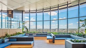 A modern interior with large windows, seating areas, and a view of the city.