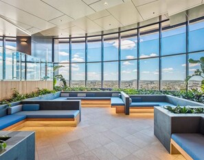 A modern interior with large windows, seating areas, and a view of the city. - Luxury 1 BDR Skytower City River Views (Brisbane City)