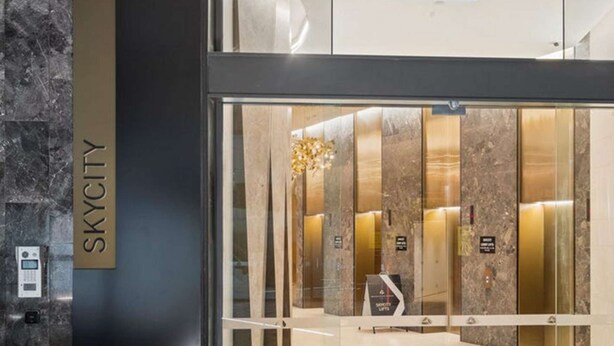 A modern elevator entrance with a marble wall and a sign reading 'SKYCITY'.