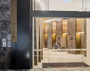Moderni hissin sisäänkäynti, jossa on marmoriseinä ja kyltti, jossa lukee ”SKYCITY”.