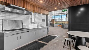 A modern kitchen with a stainless steel stove, grey cabinets, and a wooden ceiling.