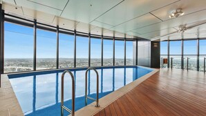 A modern indoor swimming pool with large windows offering city views.