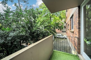 A balcony with a view of a brick building and a car parked on the street.