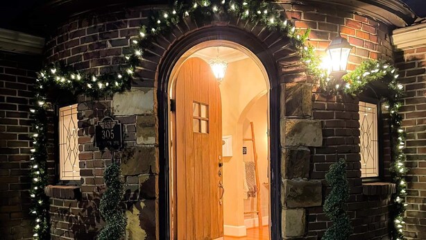 Una casa in mattoni con una porta in legno e un ingresso circolare.