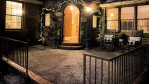 Una casa accogliente con facciata in pietra, una porta in legno e un portico con sedie.