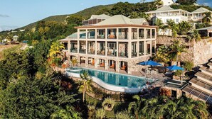 Un complexe hôtelier à plusieurs étages doté d’une piscine, entouré d’une végétation luxuriante et de collines.