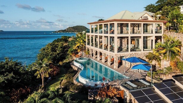 Une maison moderne avec piscine et panneaux solaires, offrant une vue sur l’océan.