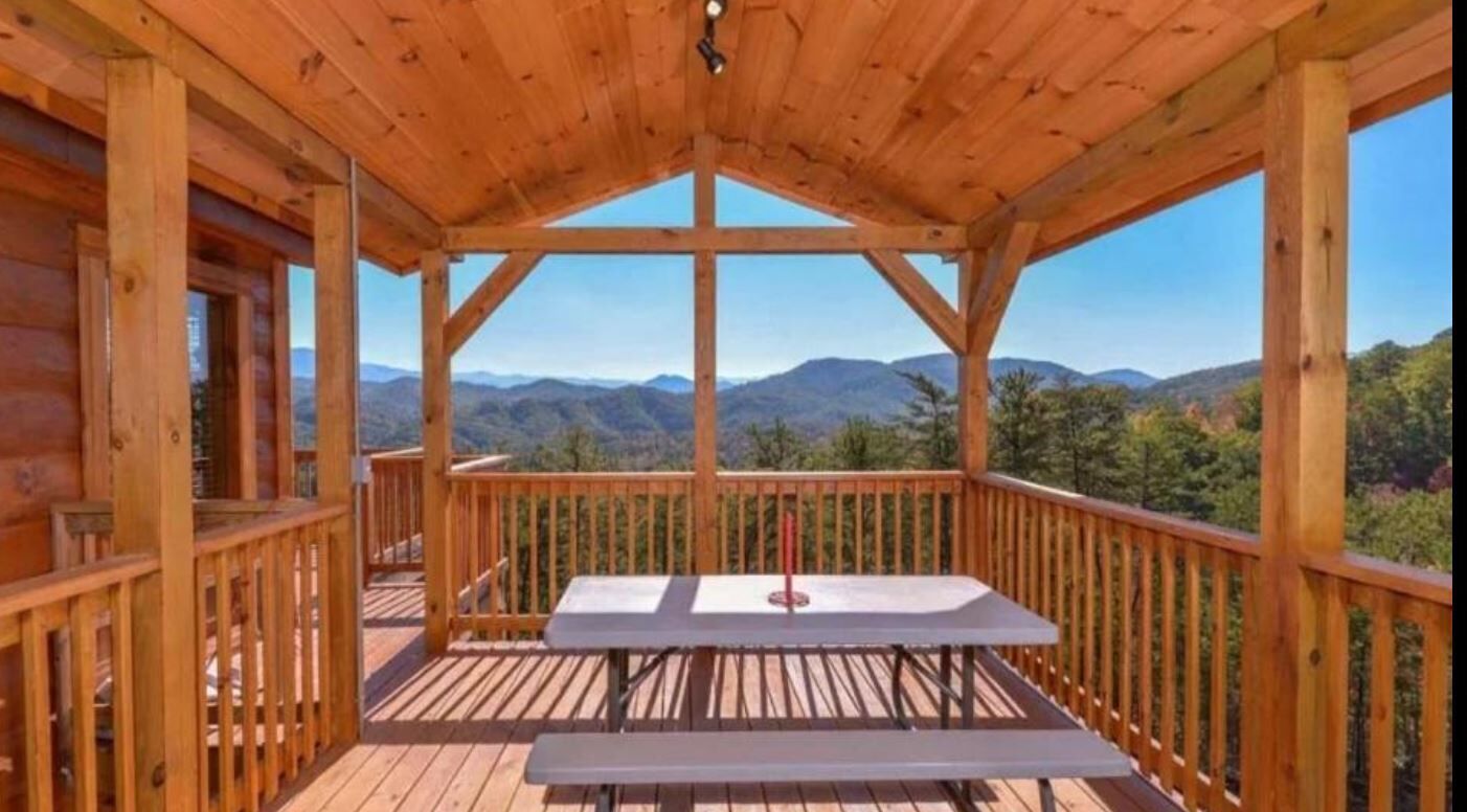 A wooden deck with a picnic table and a view of mountains.