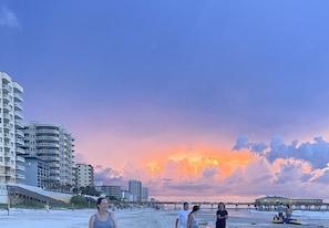 Una playa con edificios y un muelle al fondo.