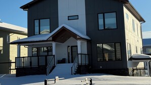 A modern two-story house with a covered porch and a snow-covered driveway. - Classy and modern suite 10 minutes away from city center (Whitehorse)